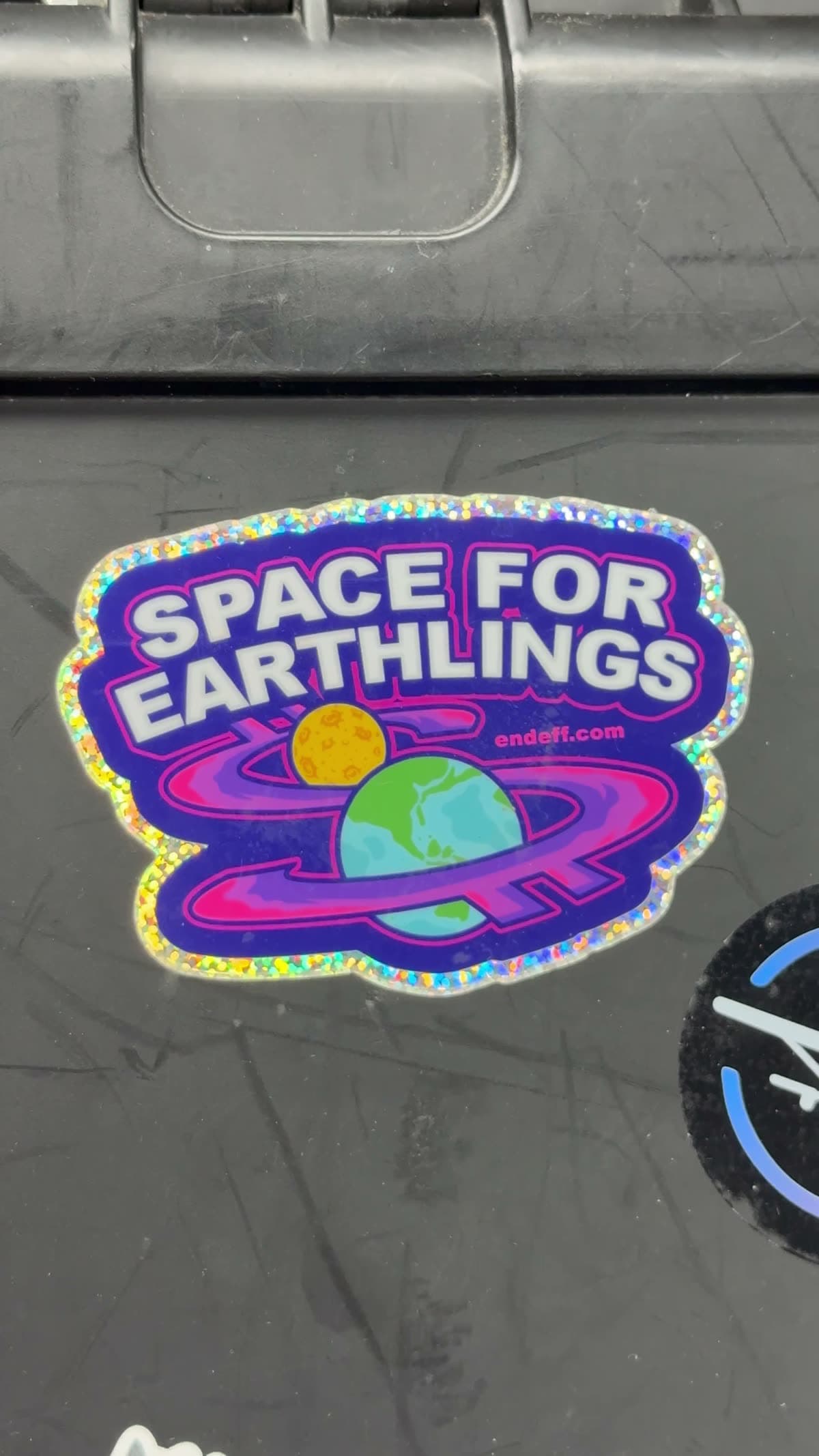 Glitter foil sparkling as the holographic sticker tilts in hand against deep red velvet